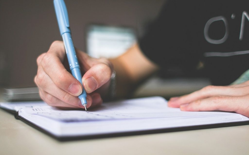 Student taking notes with blue pen 